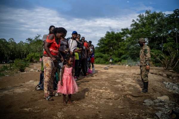 A member of the Panama National Border Service instructs a group of Haitian migrants who have just arrived in Quiebra Venado, the first indigenous community on the Panama side of the Darién Gap, after days of crossing the jungle. Darién Gap, Panama, 29 September 2021