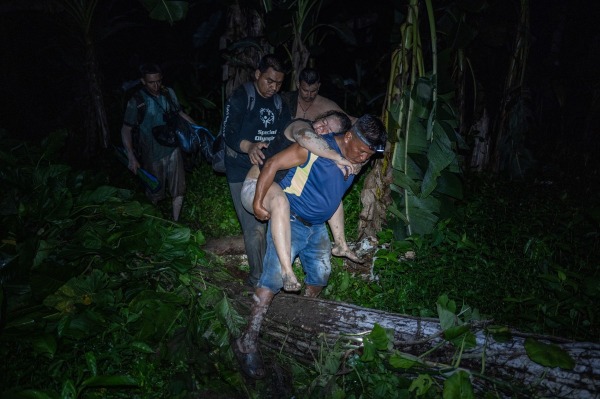 Rubén Guaynora, a local indigenous man, carries Kimberly Rodriguez, a Venezuelan who fainted several times while crossing the Darién Gap. He will help her onto a canoe that will transport her to Bajo Chiquito, where she may receive medical attention. Darién Gap, Panama, 21 September 2024