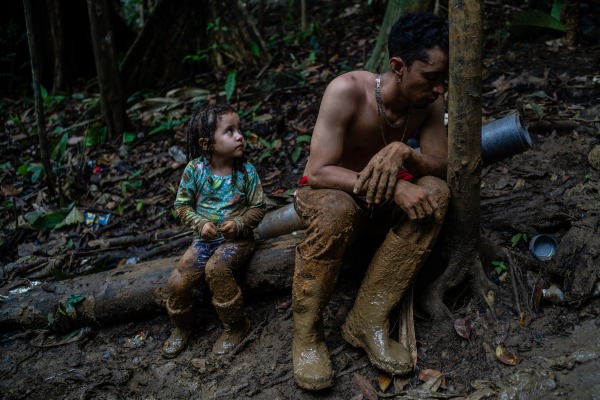 Luis Miguel Arias (28) takes a break with his daughter Melissa (4) as they climb a hill. They are from Venezuela and joined the over 250,000 migrants who traversed the gap in 2022. Darién Gap, 23 September 2022