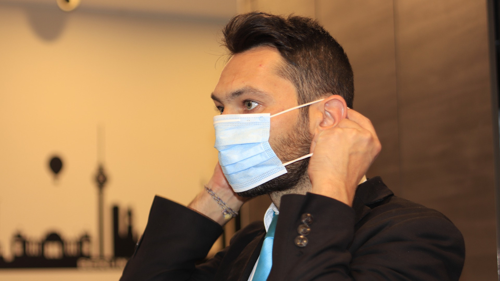 Businessman in office putting on mask 1600x900