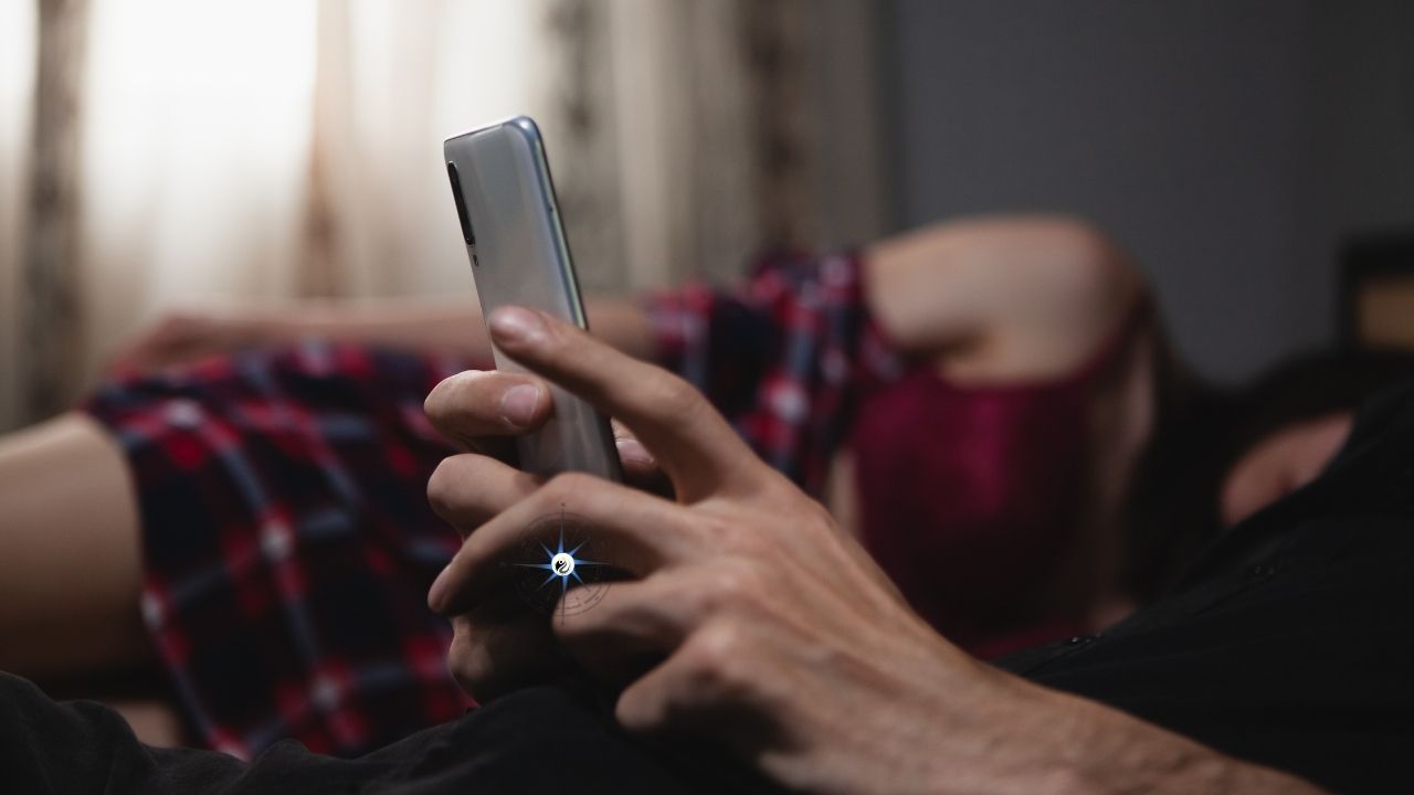 Homme sur cellulaire, partenaire au fond