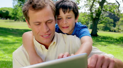 stock-footage-happy-father-and-son-using-a-tablet-computer-in-a-park