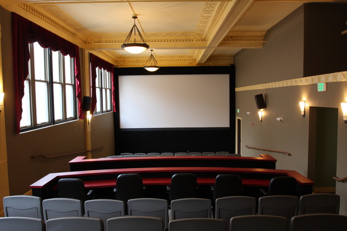 The view from the back of our auditorium showing the 20-foot screen and historic architecture. Blackout curtains cover the windows during theatrical presentations.