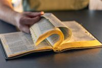 A man reads the Bible. Male hands on the Holy Bible. Close-up of the Bible.