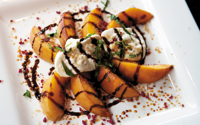 Roasted Peach & Burrata starter; soft cheese with sweet and tangy peaches and balsamic reduction please the palate. Photo by Hubert Bonnet