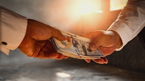 One person giving a stack of money to another person.