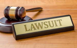 Judge's gavel with sign that reads 'lawsuit'.