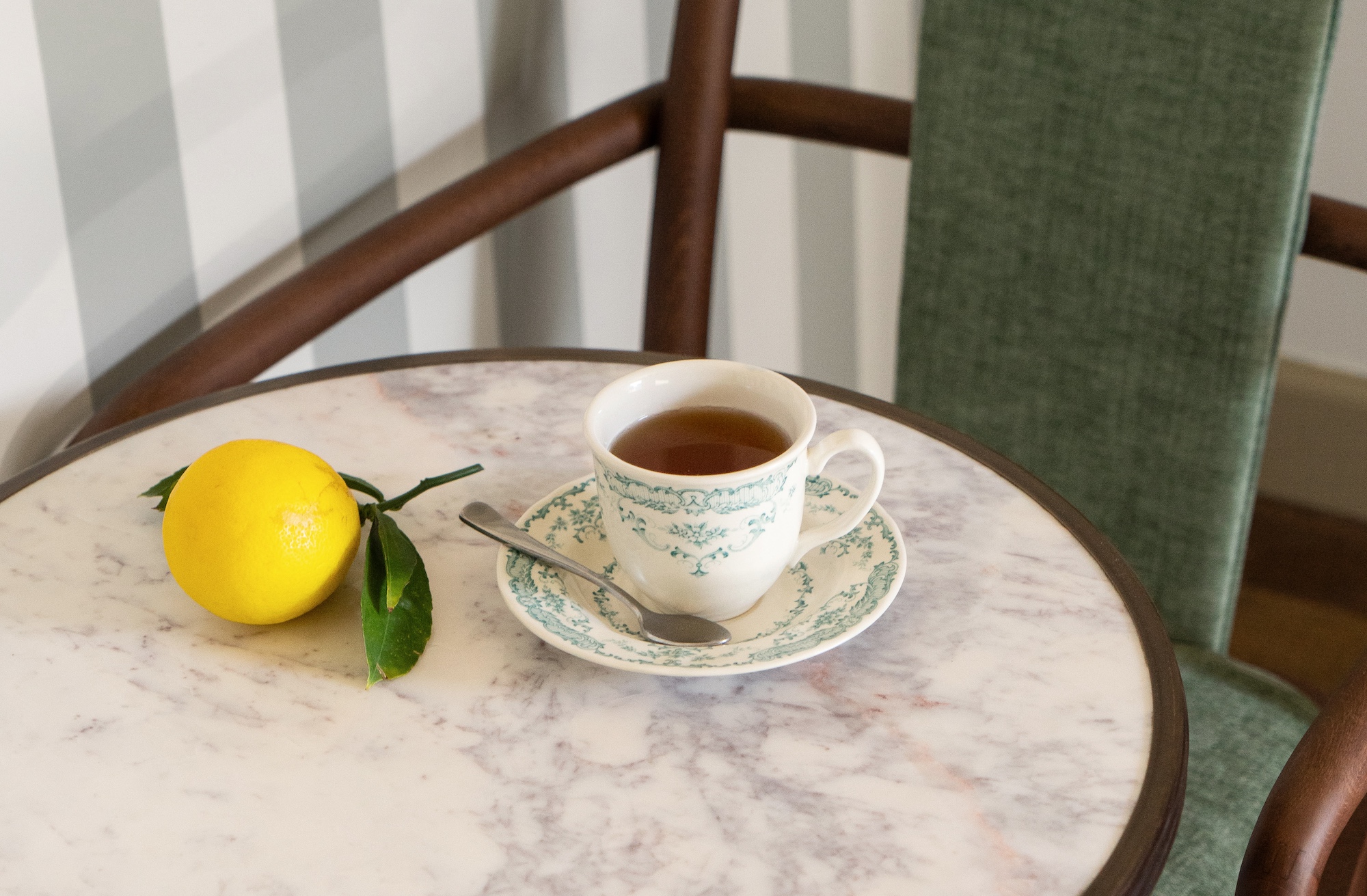 A cup of tea and a lemon on a marble table