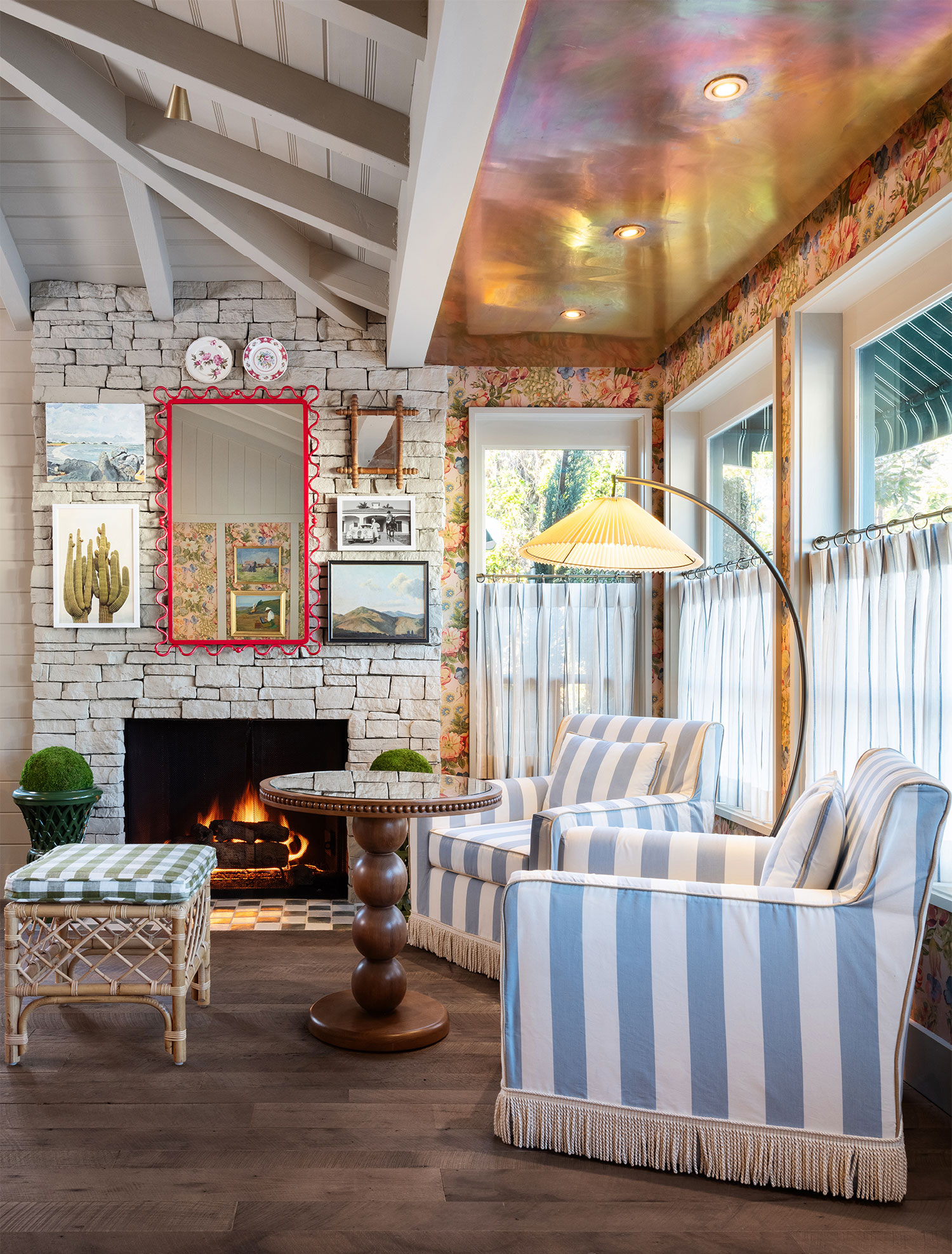 A lobby with a fireplace, two striped chairs, and a colorful ceiling.