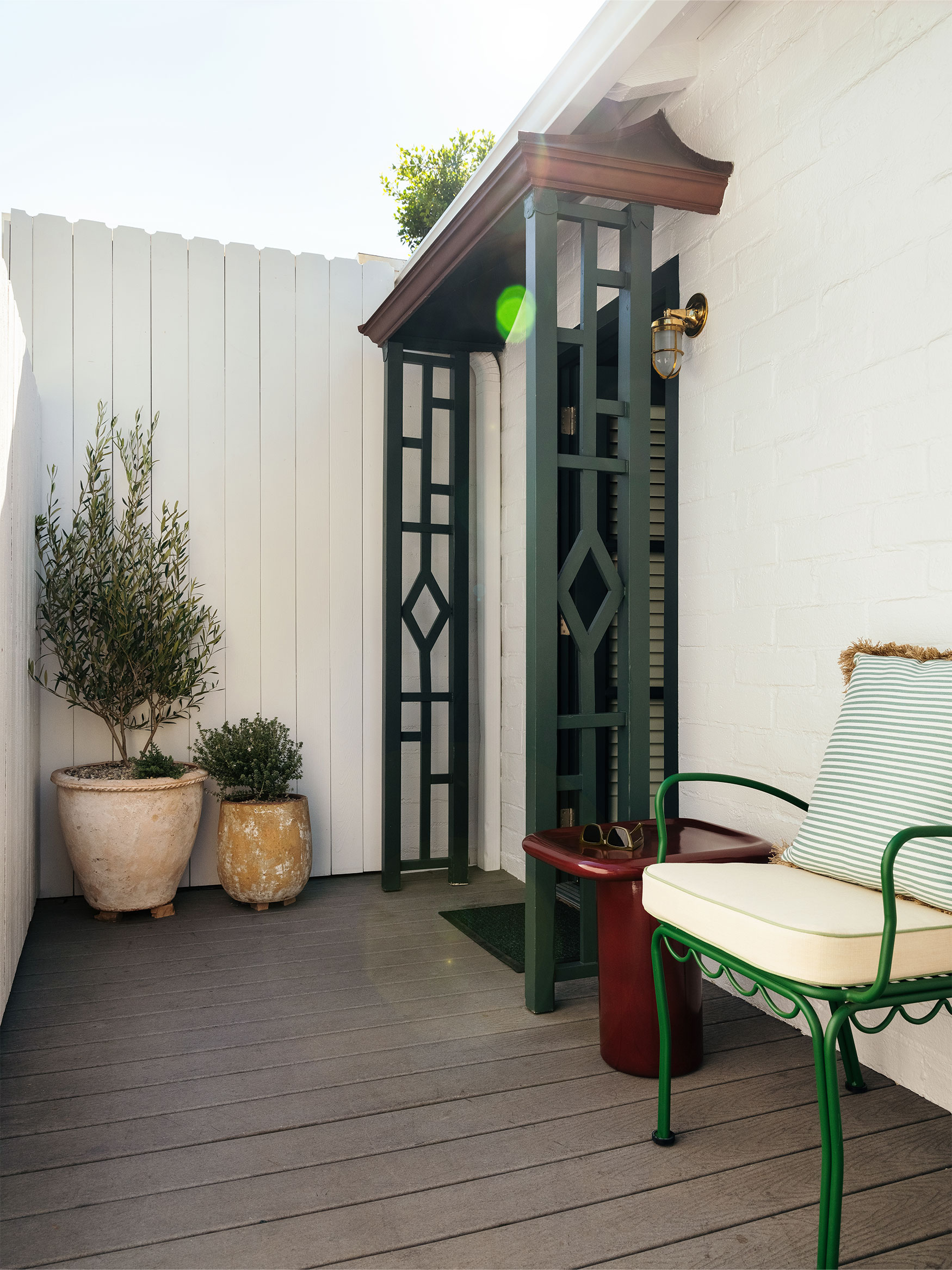 A small outdoor patio with a green metal chair, a small table, and potted plants.