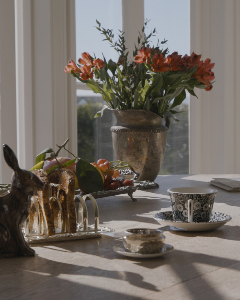 A table set with a cup and saucer, a fruit tray, and a vase of flowers