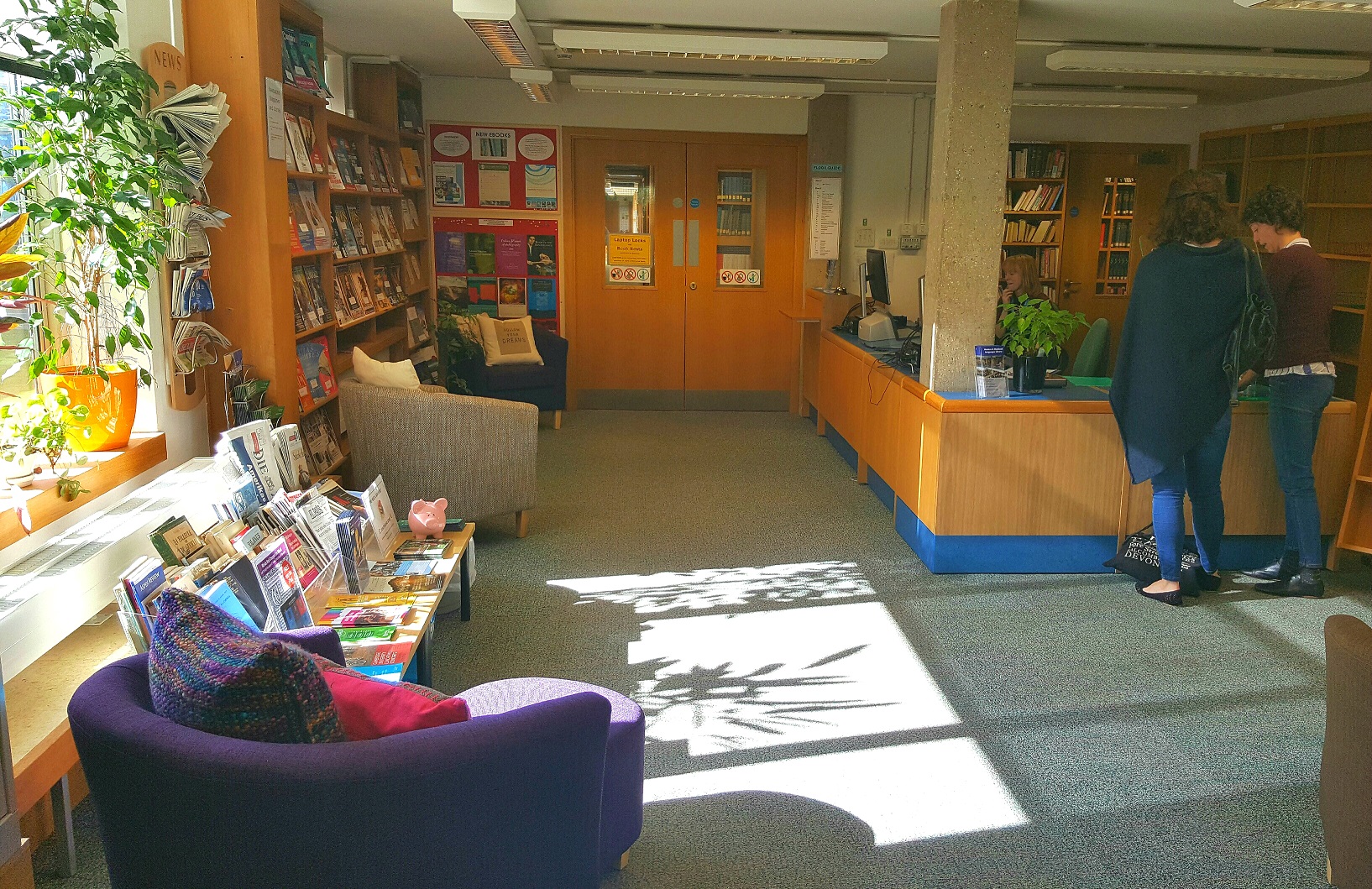 A colour photo of the MMLL Library lobby, with people standing next to the self-service machine