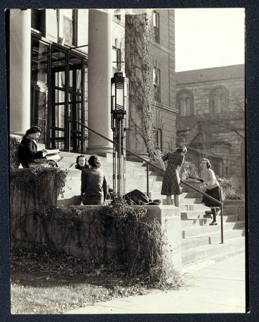 black and white photograph of students siting with books on steps outside of Derham Hall