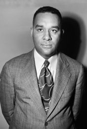 Black and white photograph of a Black man in a suit looking above the camera