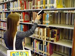 Student grabbing a book from the library's bookshelves