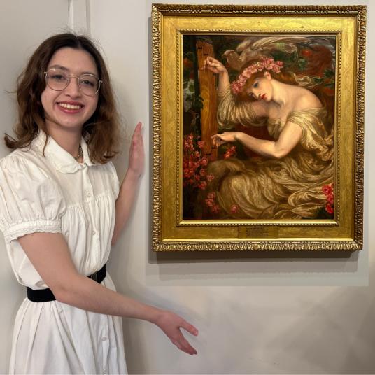 In this photomontage, a smiling young woman, wearing a white dress with a black belt, gestures toward a painting that appears to float beside her. In the painting, a red-haired woman in a cream-colored dress sits with her head inclined toward a stringed instrument she plays.