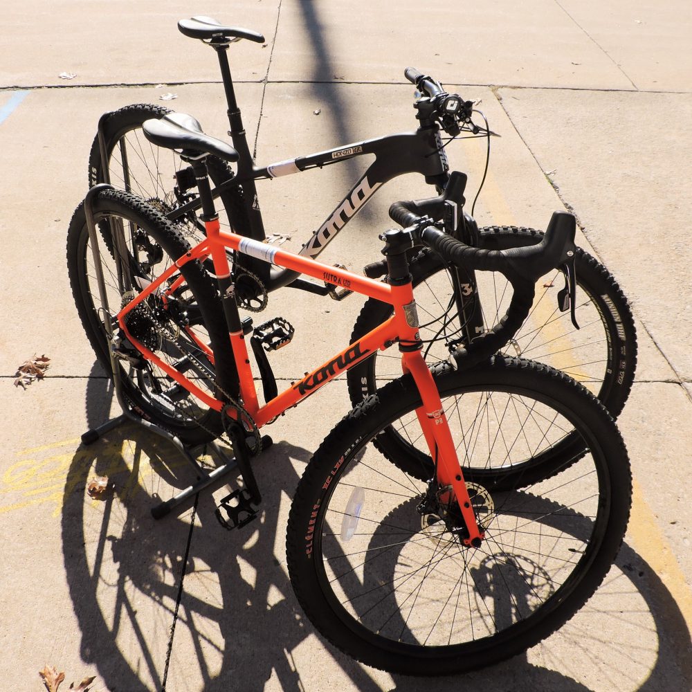 Two Kona bikes, back is black front bike is orange