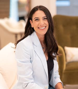Picture of Jennifer Friedman smiling at the camera while holding a baby.