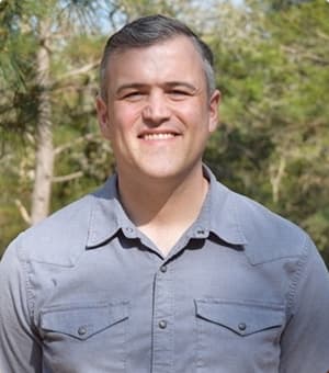 Joe Dickson, a former global director of quality standards at Whole Foods, standing in front of a backdrop of trees, smiling.