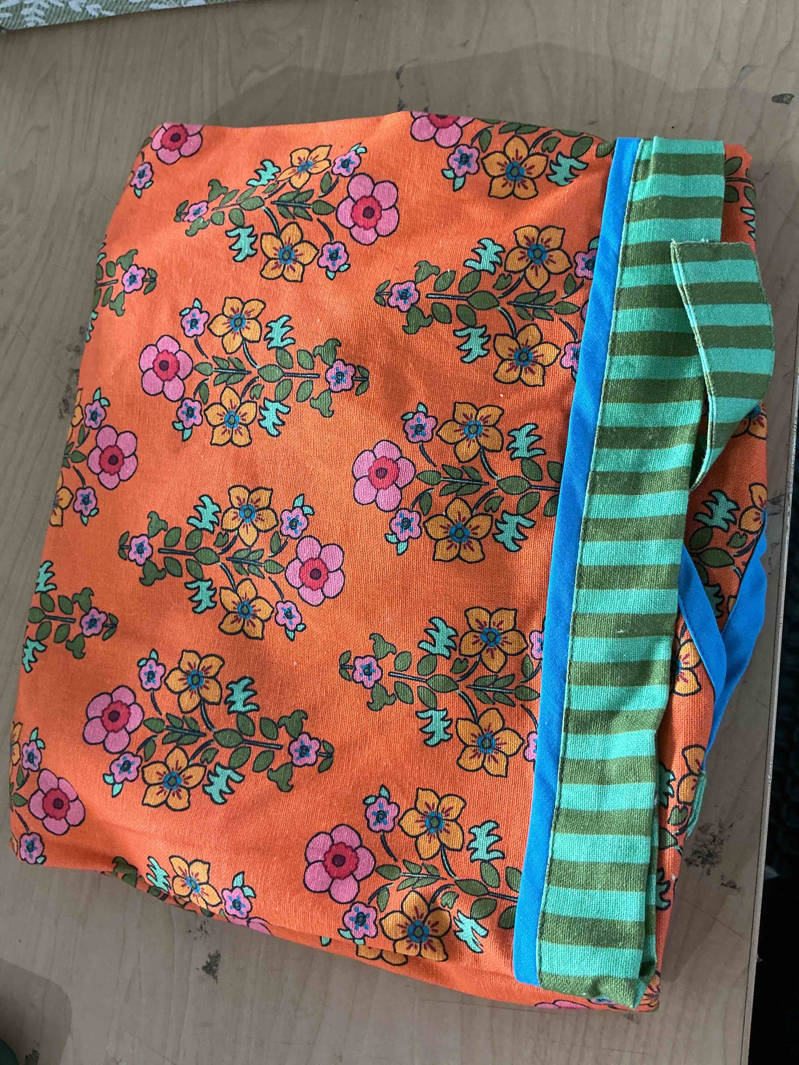 Condition photo showing New/Like New for hot grill summer apron an orange and green floral printed kitchen apron featured the embroidered word, hot grilled summer across the chest frankfurt candle company