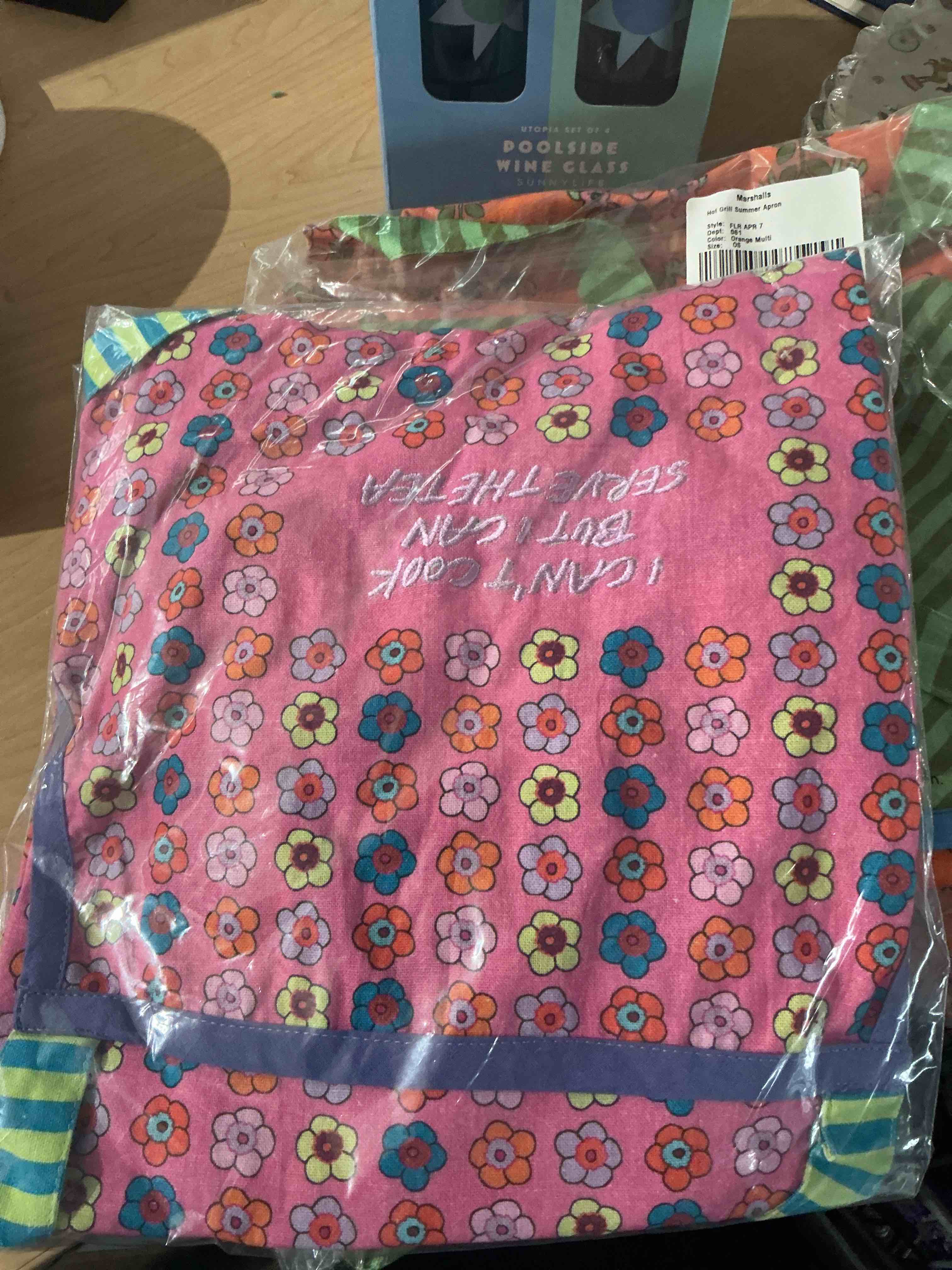 vibrant, pink retro style formal kitchen, apron featuring embroidered text that reads i can’t cook, but i can serve the tea shades of orange, purple, blue, and yellow, detailed with a cling purple roller trim near the bottom