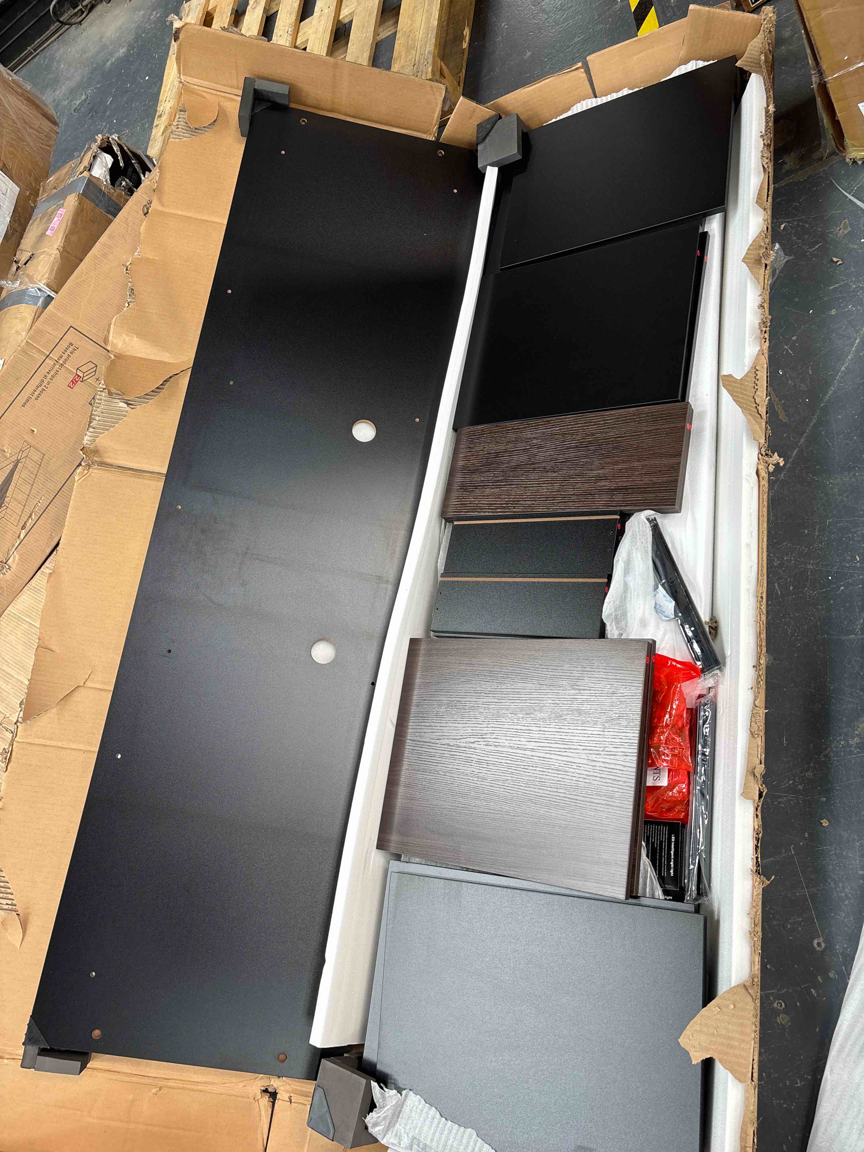 The image shows the unassembled components of a piece of furniture, likely a cabinet or a wardrobe, still in its original packaging.