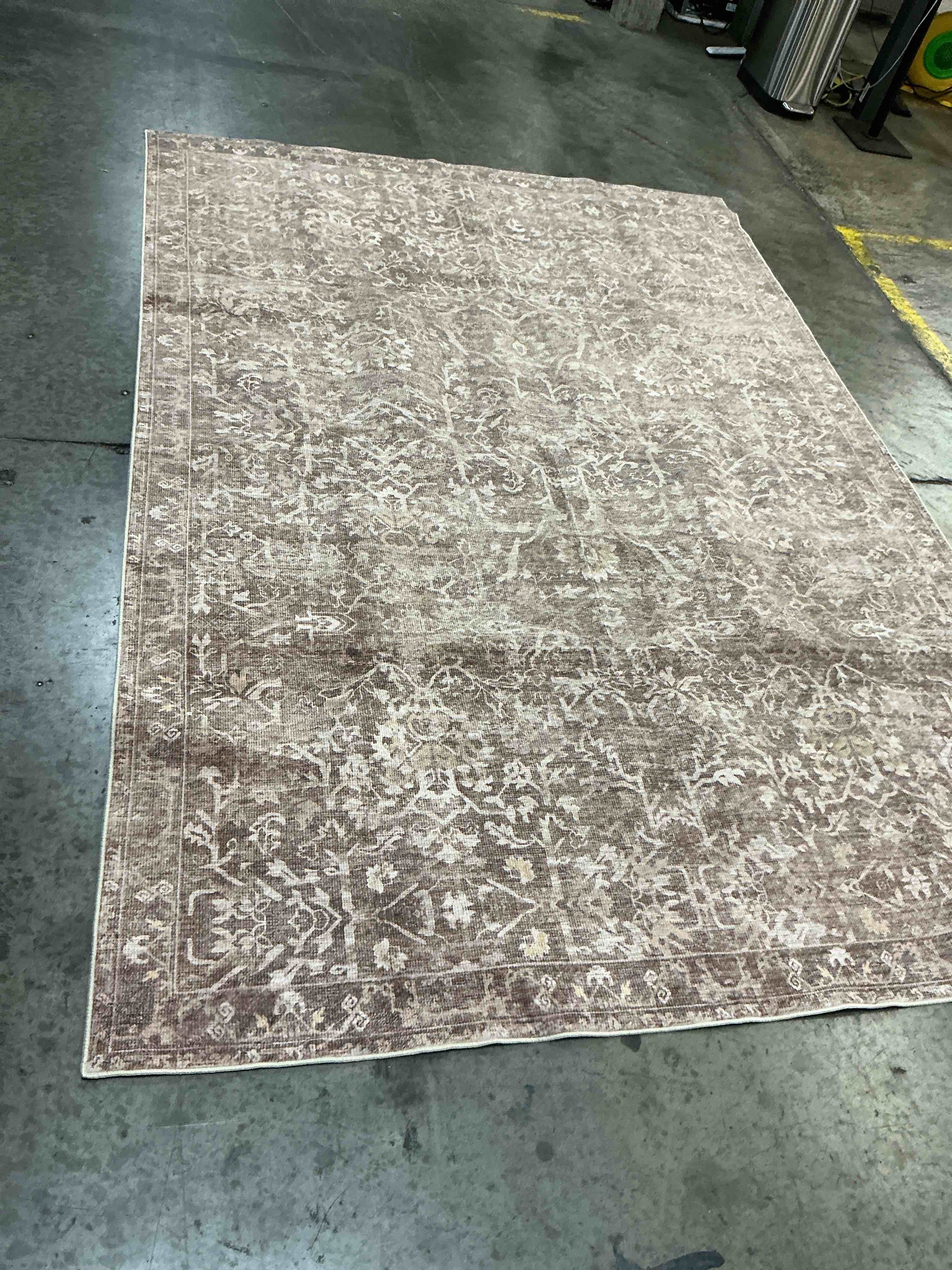 Condition photo showing Good Condition for earth/natural washable rug features a distressed, traditional floral motif in earthy brown and neutral tones 6’x9’