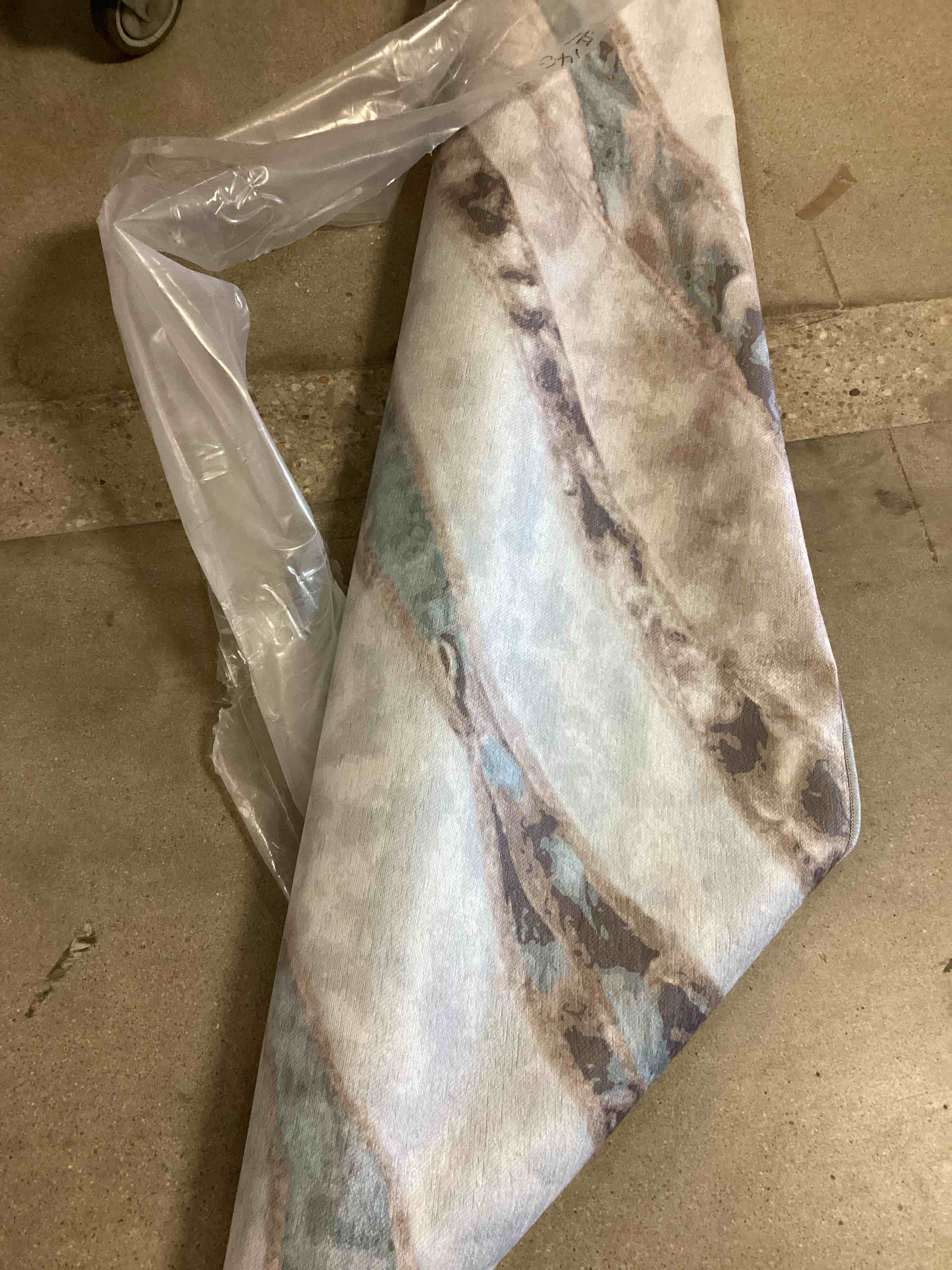 The carpet in the image has an abstract design inspired by agate or marble, with fluid shades of blue, gray, ivory and beige