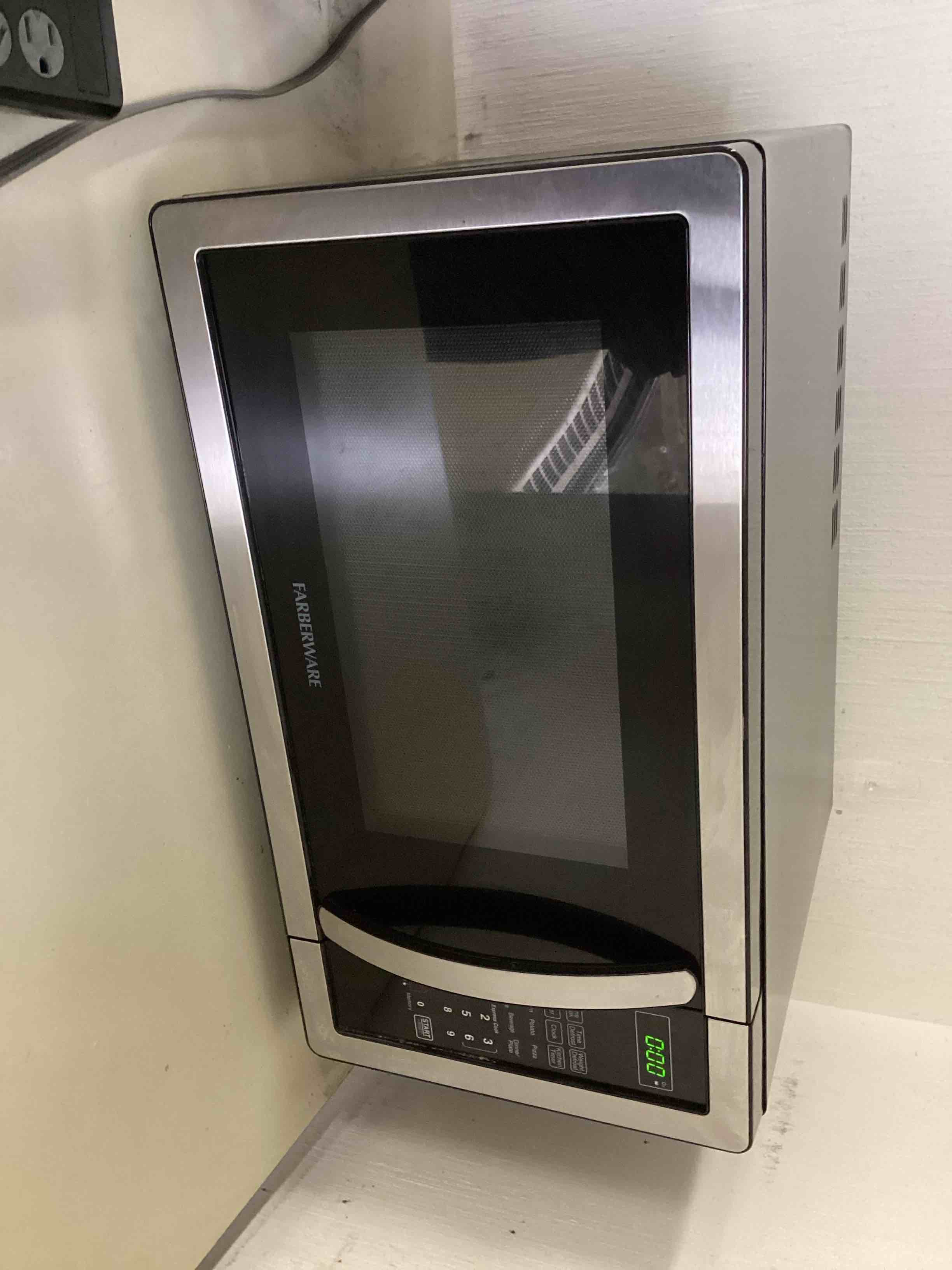 Condition photo showing As Is for Farberware 1.1 Cu. Ft. Countertop Microwave Oven – 1000 Watts Power, Auto Cook Settings, Defrost, Easy Clean and Child Safety Lock - Stainless