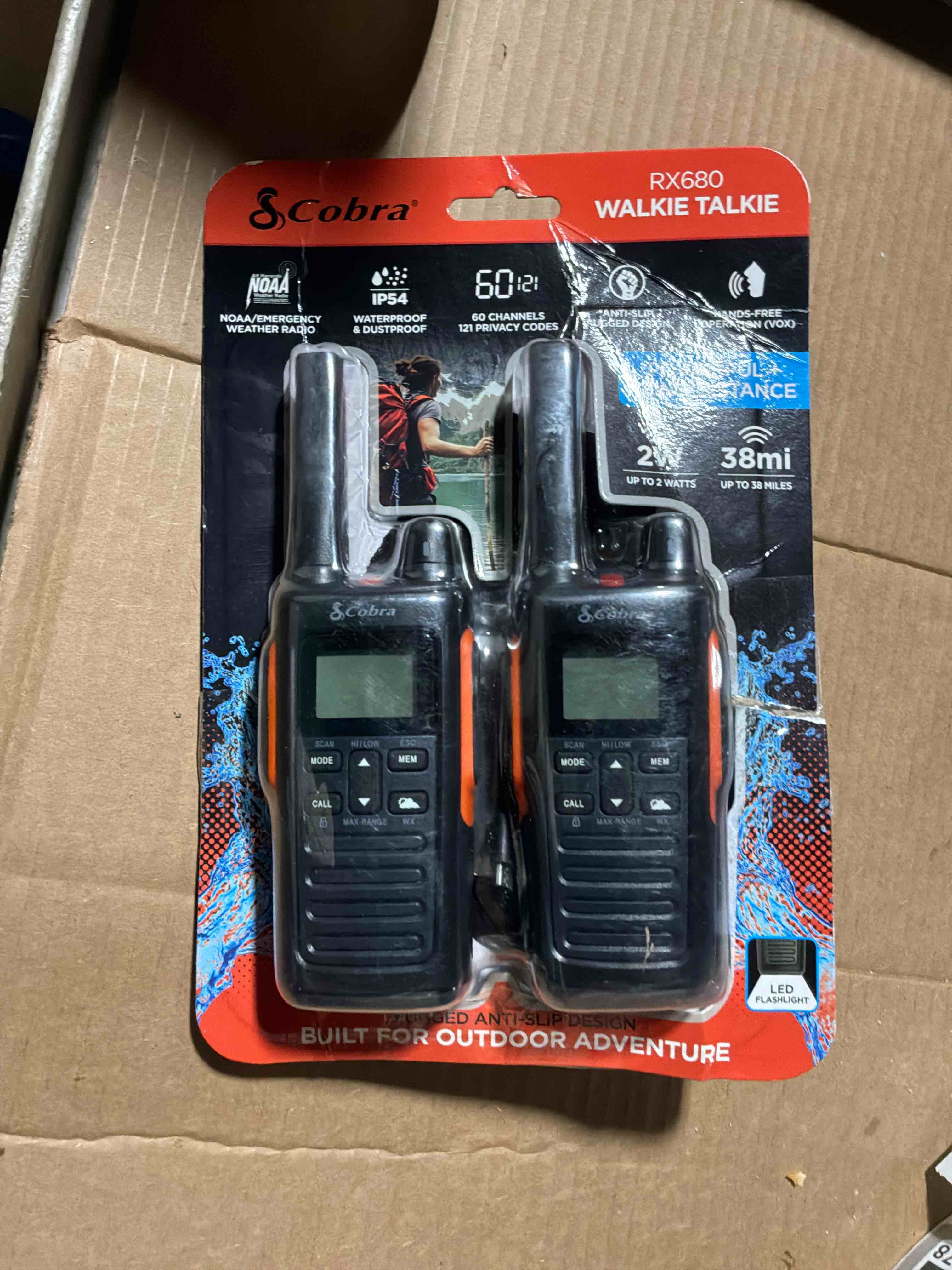 Condition photo showing New/Like New for Cobra RX680 Walkie Talkies (2-Pack) - Rugged & Splashproof Two Way Radios Long Range, IP54 Water Resistant Design, 60 Pre-Programmed Channels, Weather Alerts, Included Charging Dock (Black/Orange)