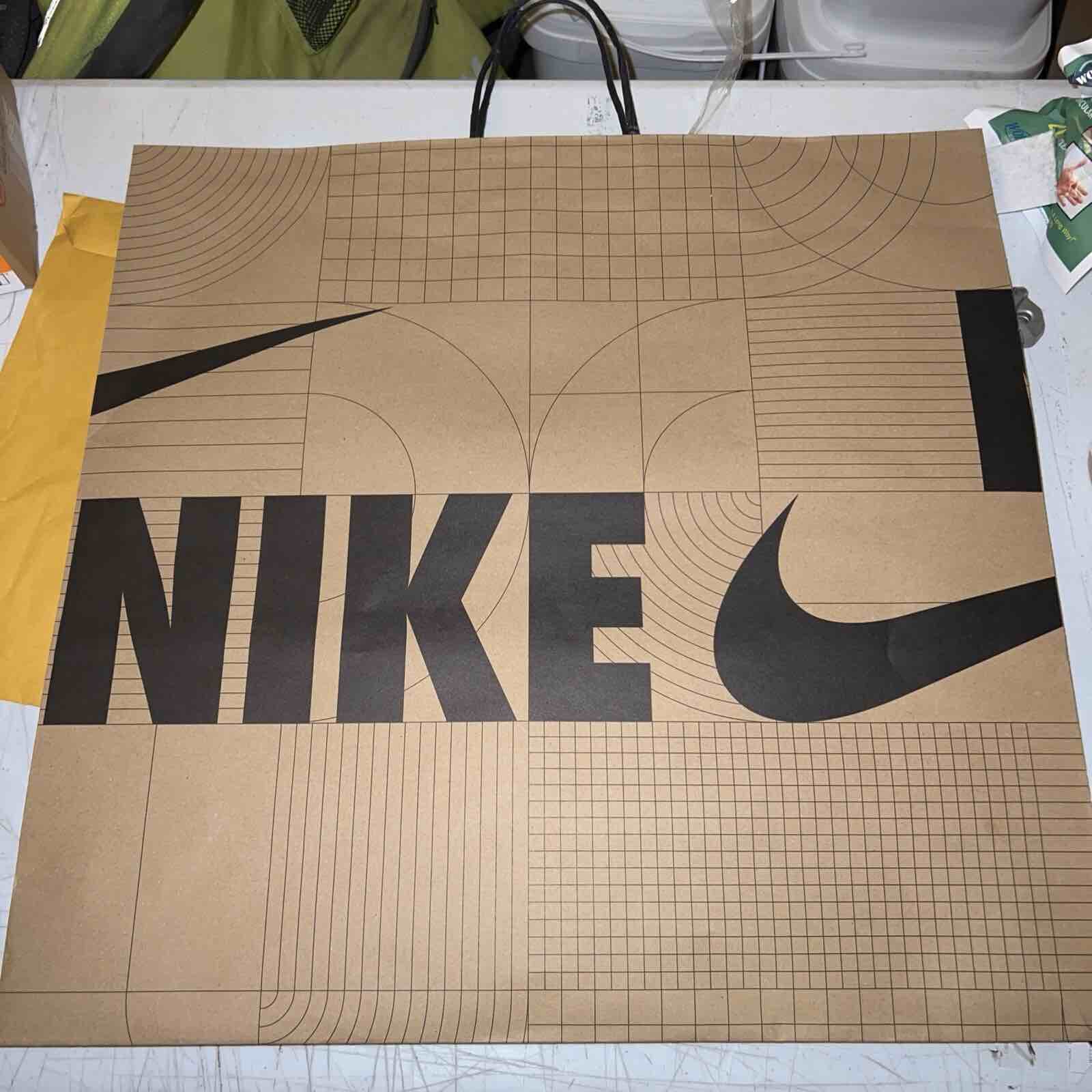 Condition photo showing New/Like New for Bag features a distinctive brown Kraft paper design with grid pattern and printed wood veins,along with the swoosh logo and the name Nike