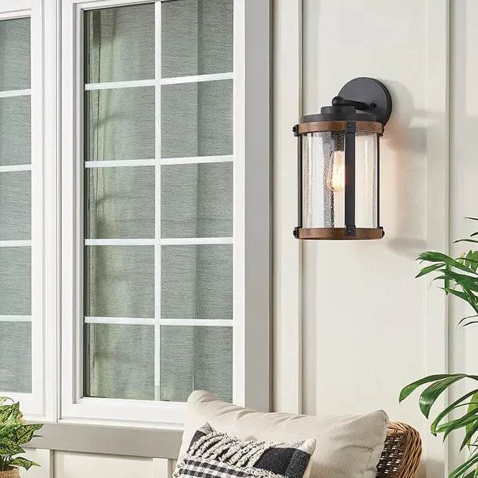 Barrington 1 Light Outdoor Wall Light features a distressed black metal and a wood tone finish that will complement your homess overall appeal. With clear seeded glass, it's sure to enhance the nostalgic touch you're looking for