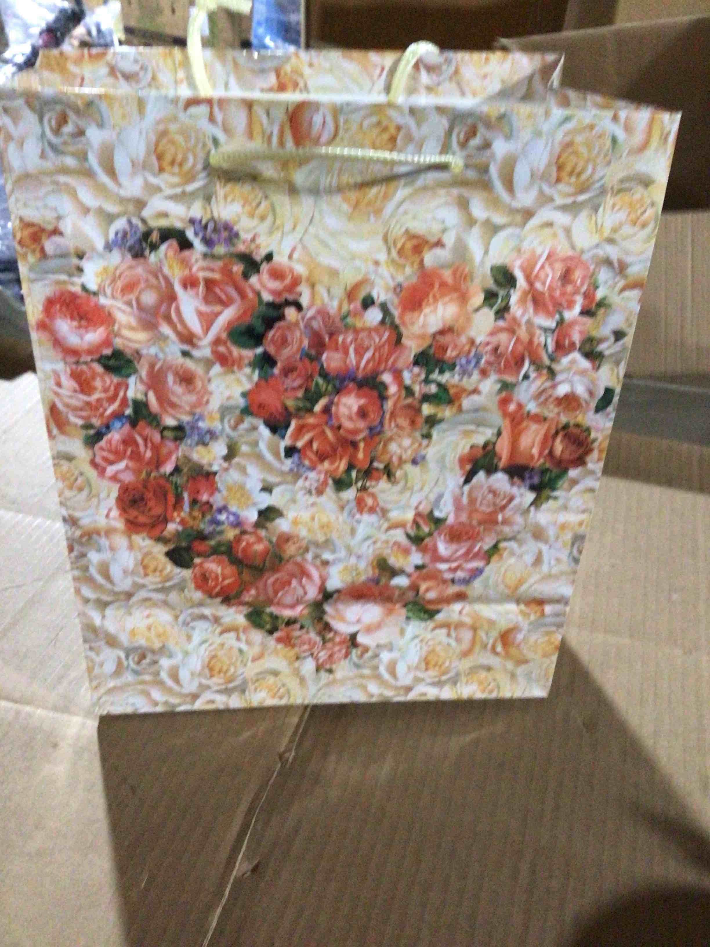 Paper gift bag with a floral print of roses in orange  tones