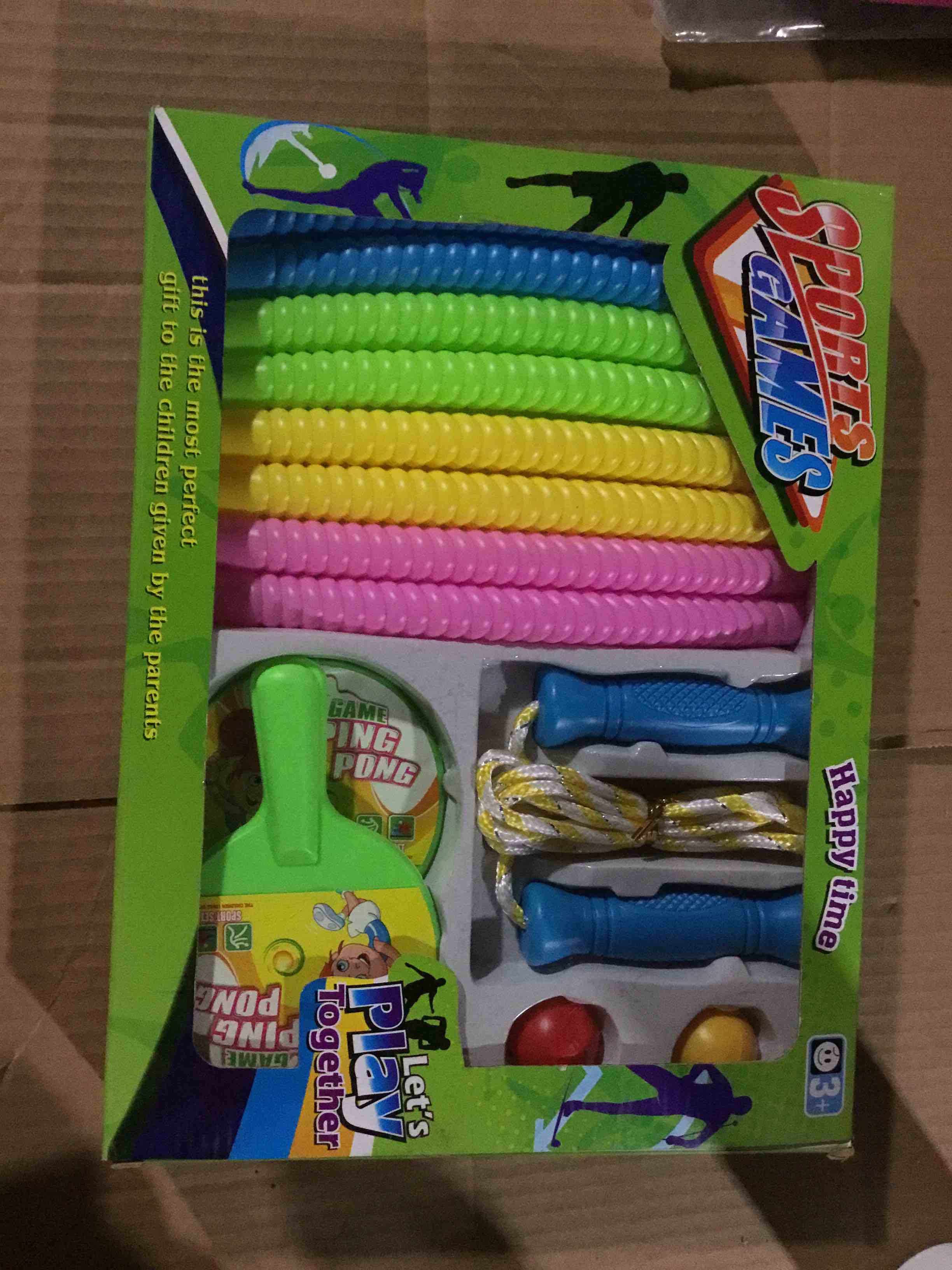 Box with a set of sports toys that includes colored jump ropes and a ping pong game