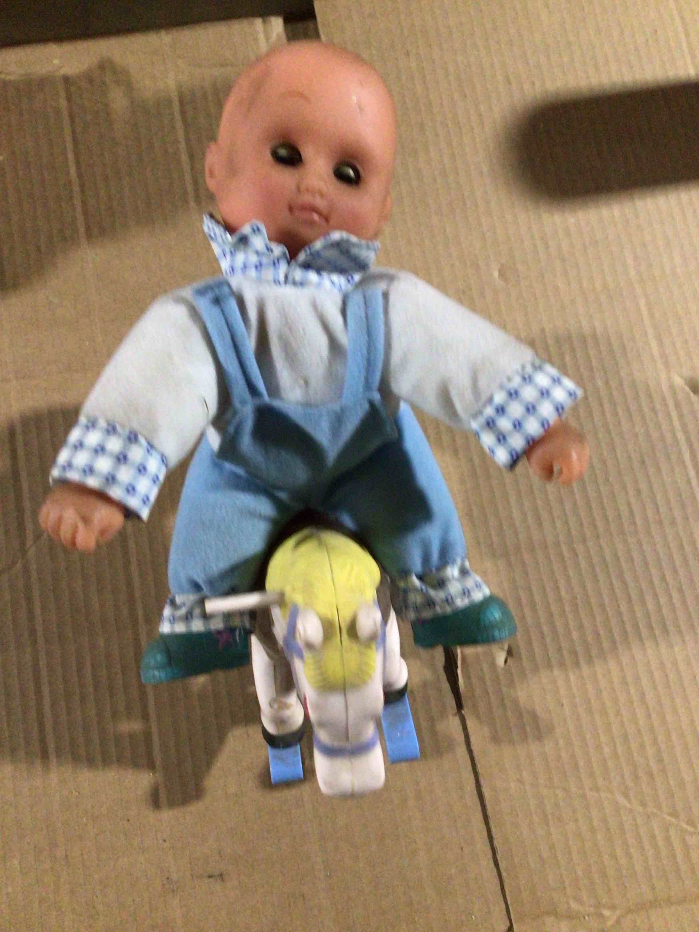 Condition photo showing As Is for Baby doll sitting on a toy horse 