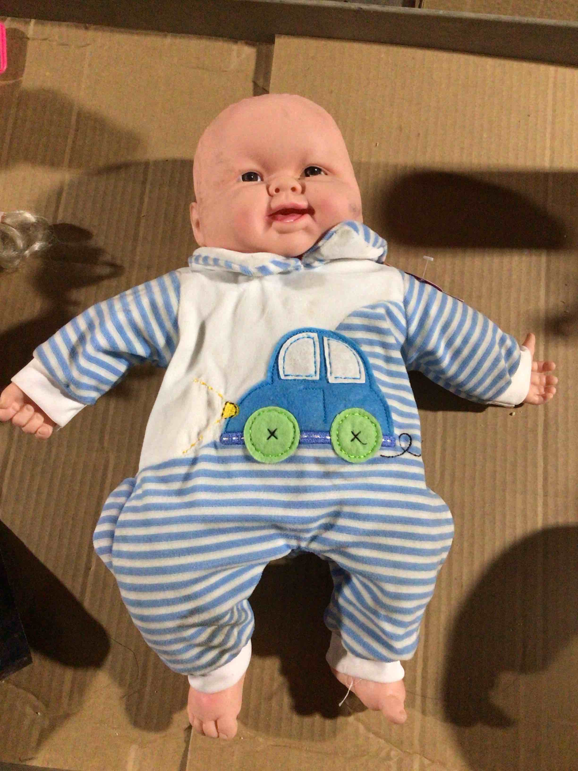 Toy baby doll with a soft body and a suit with blue stripes and an embroidered car