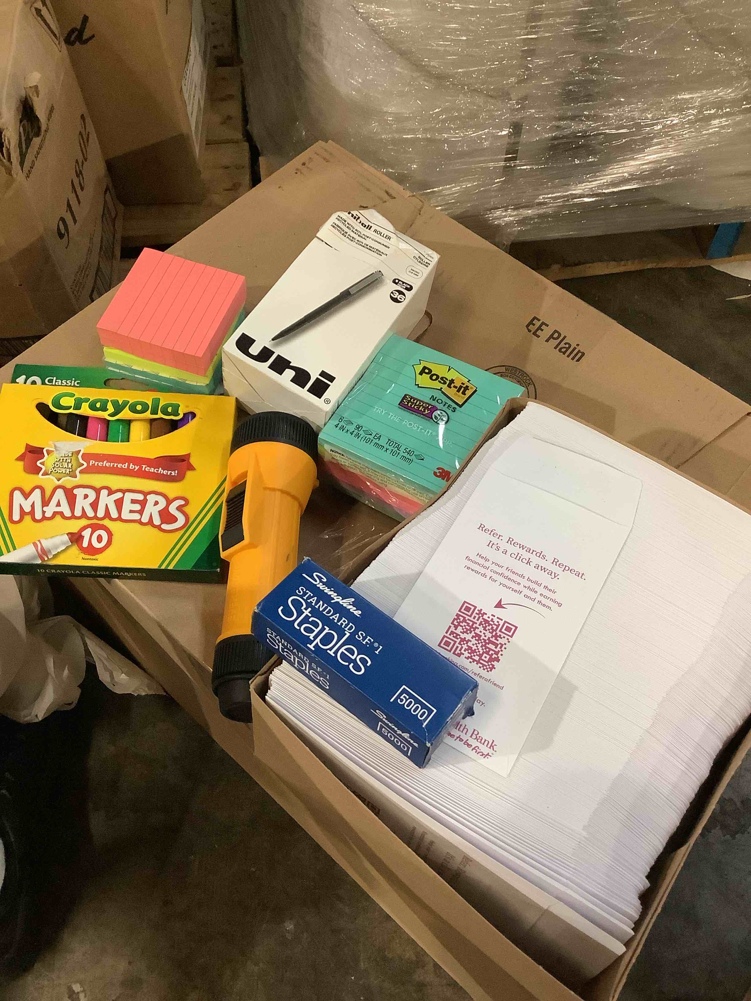 assorted office supplies: flashlight, staples, assorted poster, notes, bank, envelopes, Crayola markers, roller pins, and more