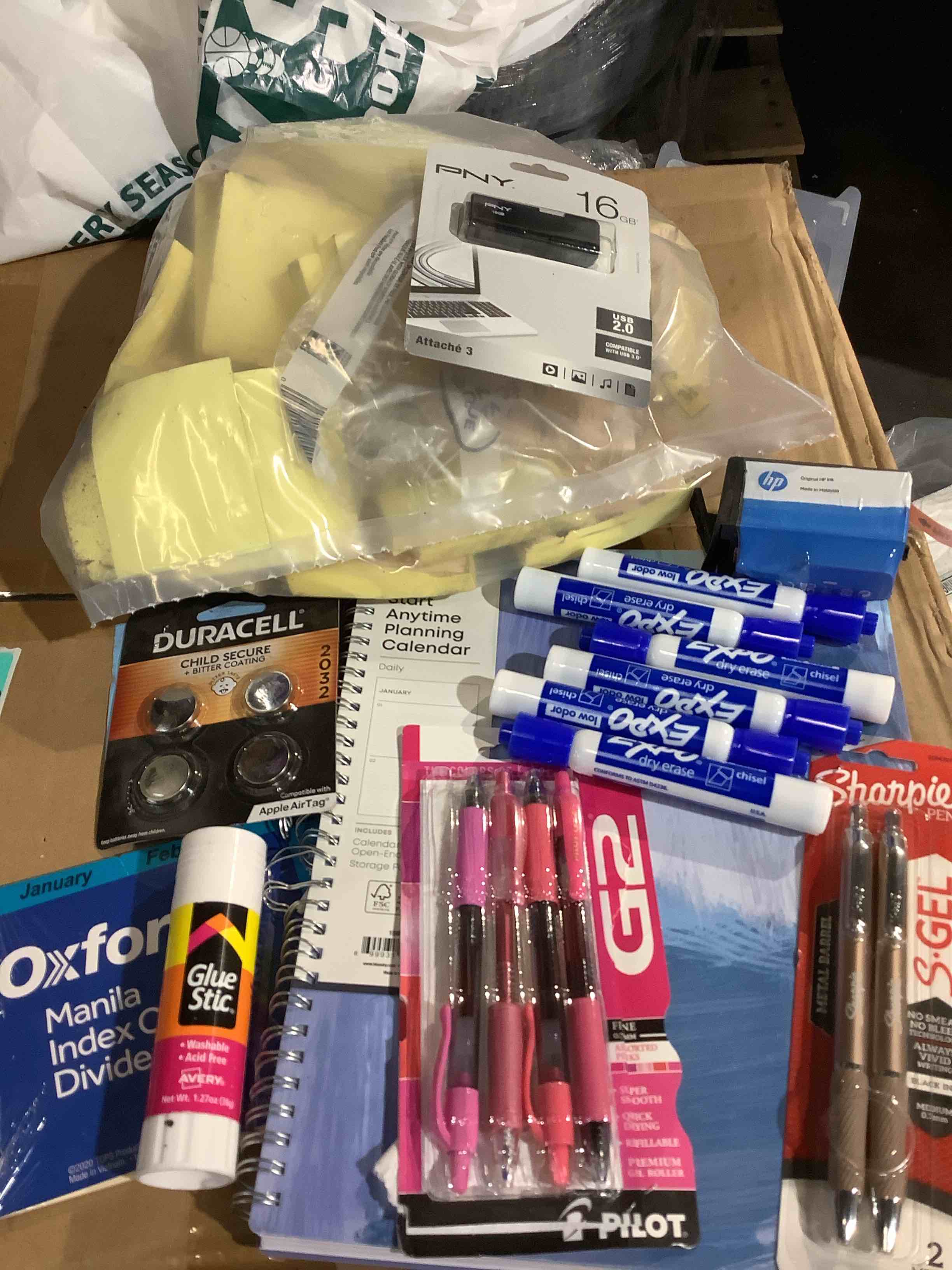 assortment of office supplies: index card dividers, Duracell batteries, glue glue, decorative pins, expo, dry erasers, Post-it notes, and more