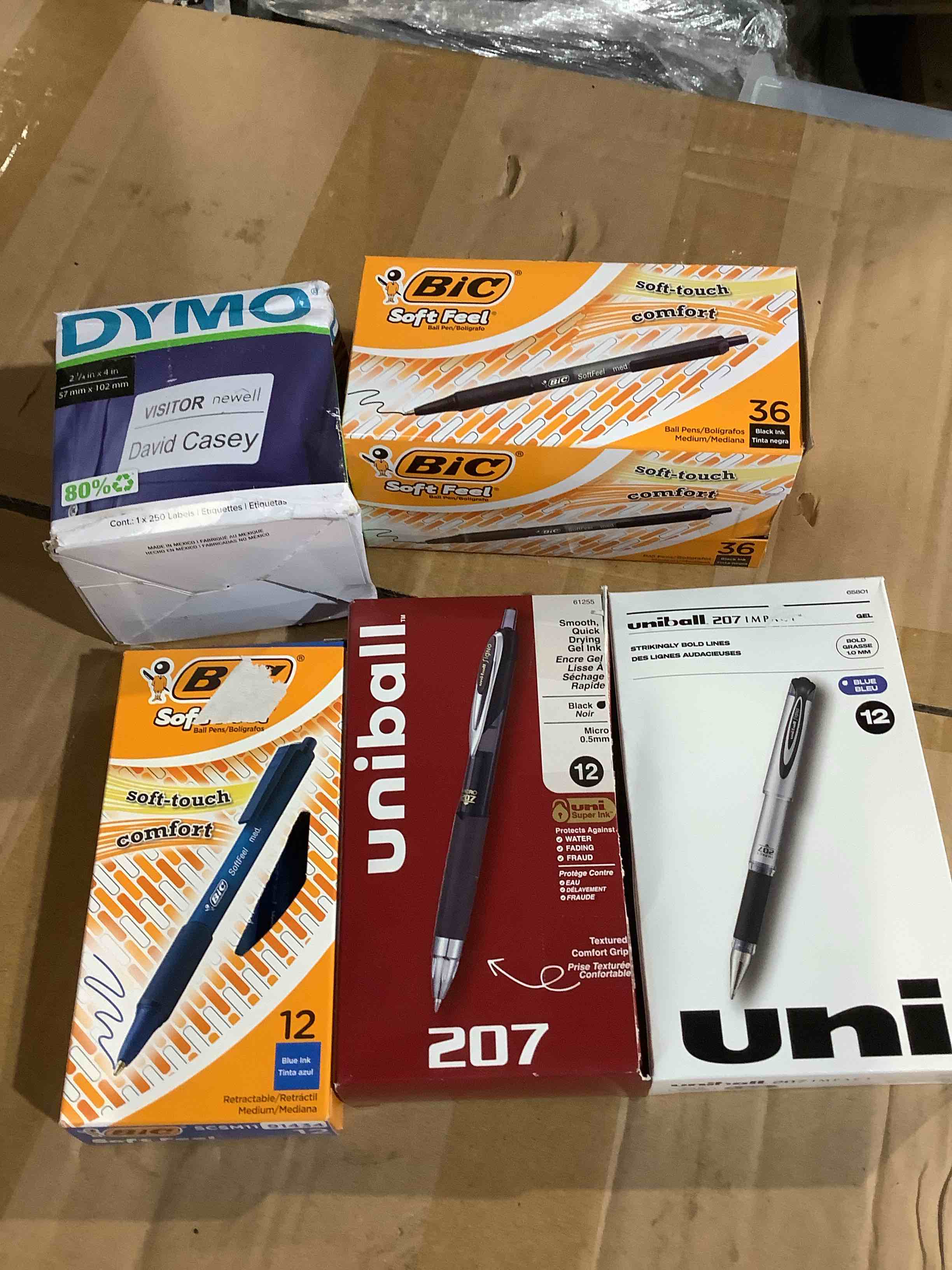 assortment of office supplies: dymo labels, bic pens, uniball and more