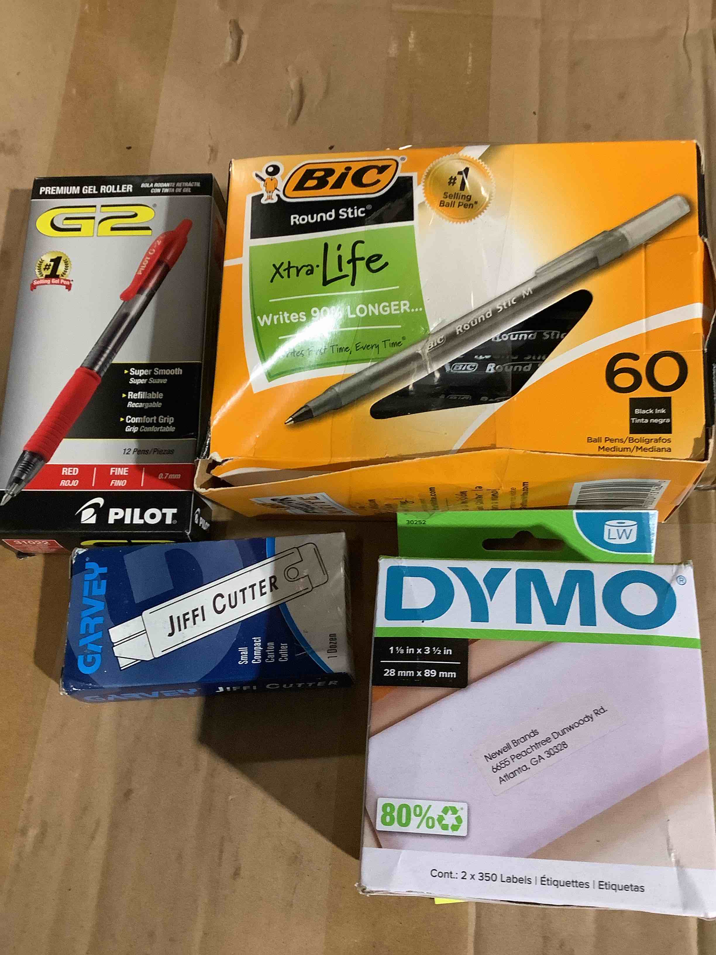 assortment of office supplies:Dymo labels, BIC black ink pens, jiffy cutters, G2 pilot, red pens