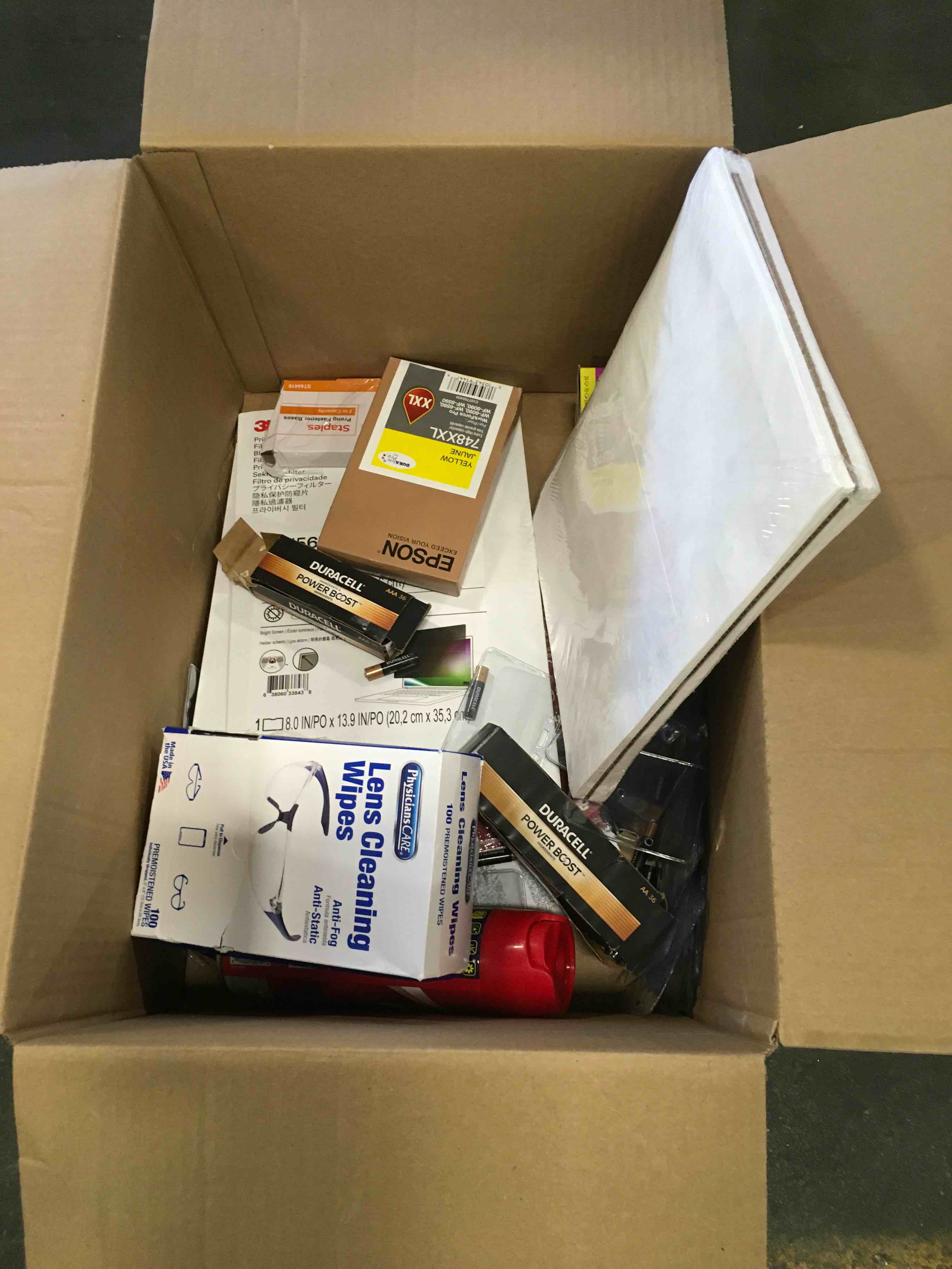 Assorted box of Staples office Supplies including Lens Cleaning envelopes post-it Duracell and more