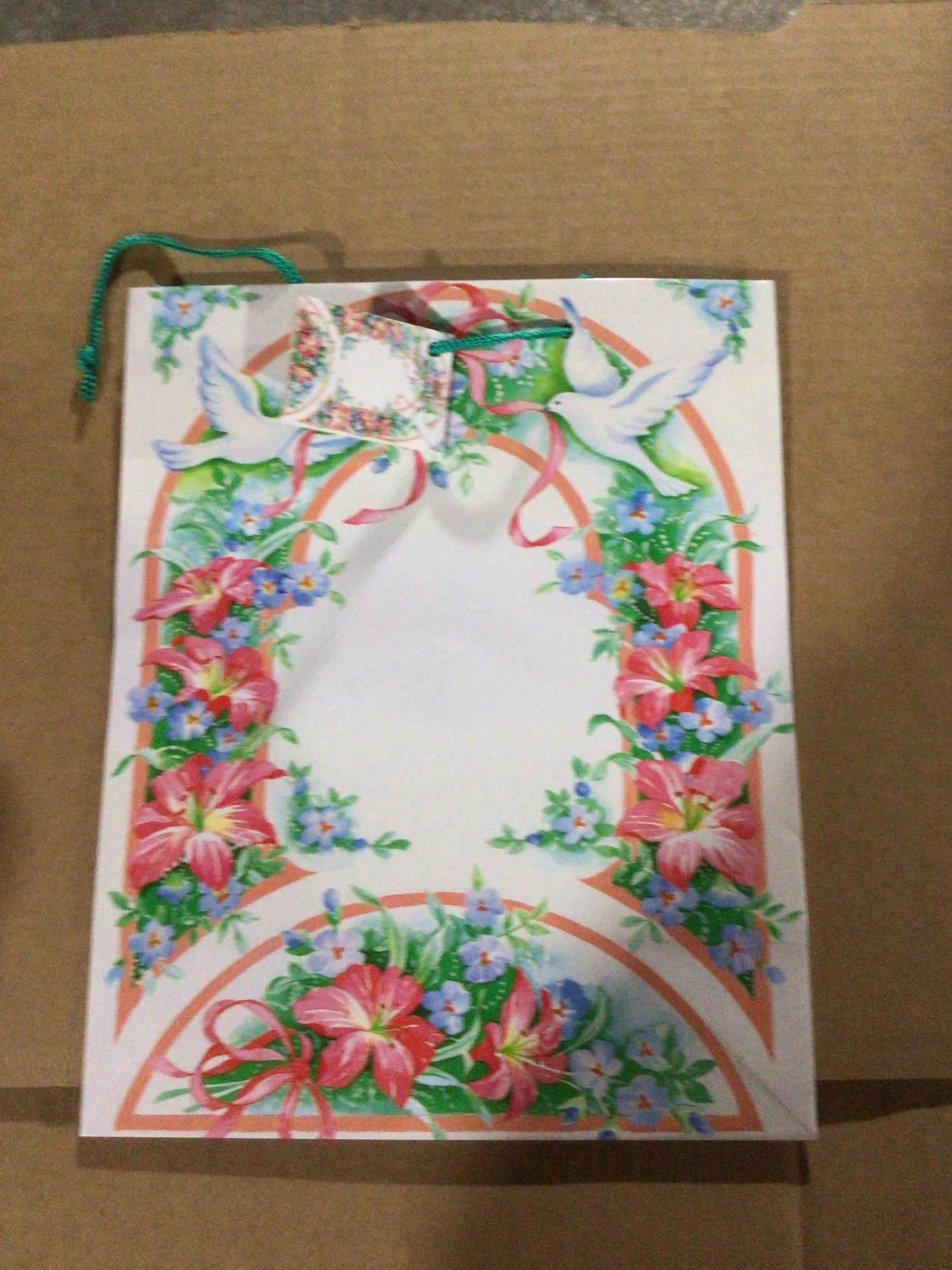 Paper gift bag that features a floral design with pink flowers 