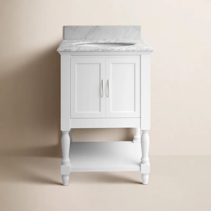 Hampton 24'' White Pinewood Single Bathroom Vanity with Open Base Shelf and Open Space Cabinet with Chrome Handles and Handpainted Carrara Stone Top. Wicker basket accesory included, Front corners of sink need glued back together, small paint chip between cabinet doors. 35'' H X 24'' W X 22'' D