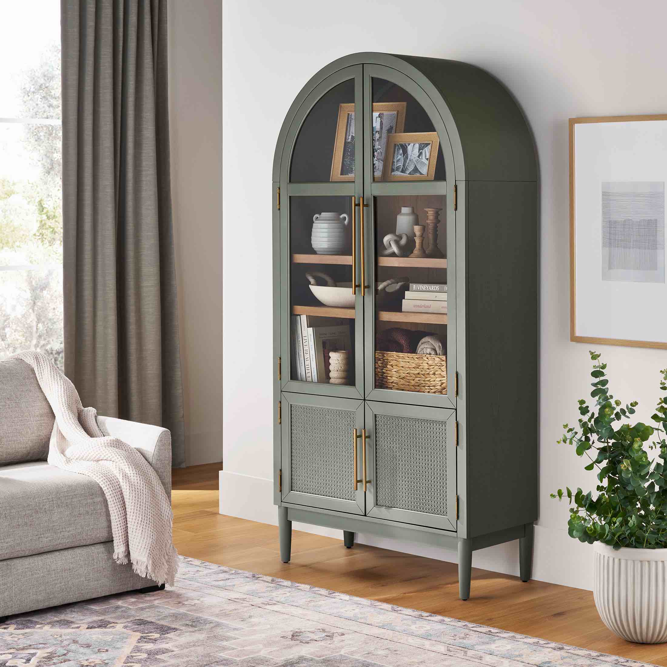 member's mark enzo storage cabinet, glass arch doors, 4 tier shelves, rattan base cabinet doors for underneath storage in green, gold brushed metal handles, natural finish interior. cut on door edge, does not affect functionality. 36"l x 17.5"wx 74h" 