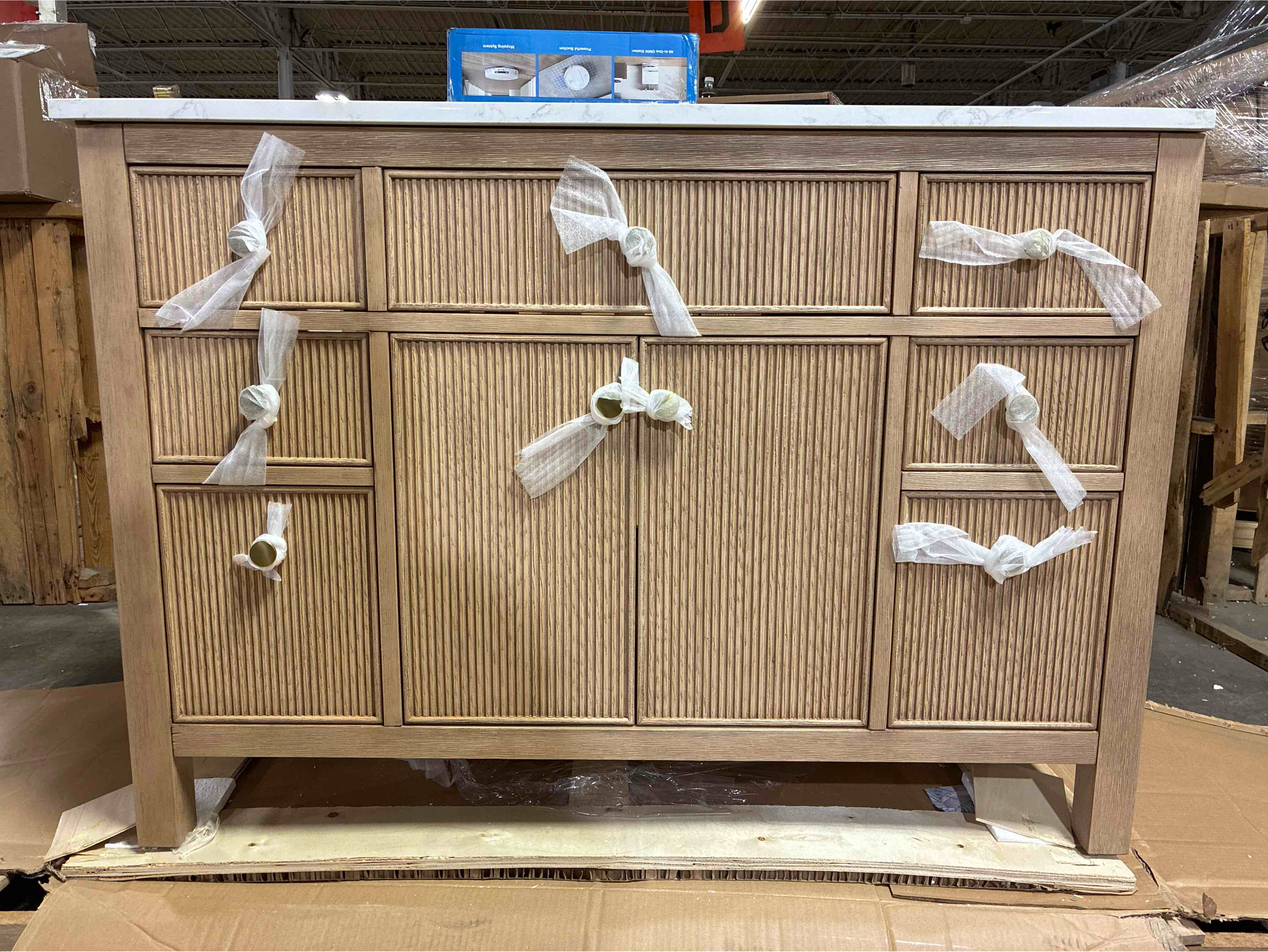 Condition photo showing As Is for Lala 48" Spruce Wood Hand Carved Single Bathroom Vanity with Grain White Stone Countertop, 7 Drawers, 1 Open Space Cabinet, and Gold Brushed Knobs. 2 thin scratches and 2 minor chips along top, cosmetic level chip on right front side, top can be filled and repainted. 34'' H X 48'' W X 22'' D