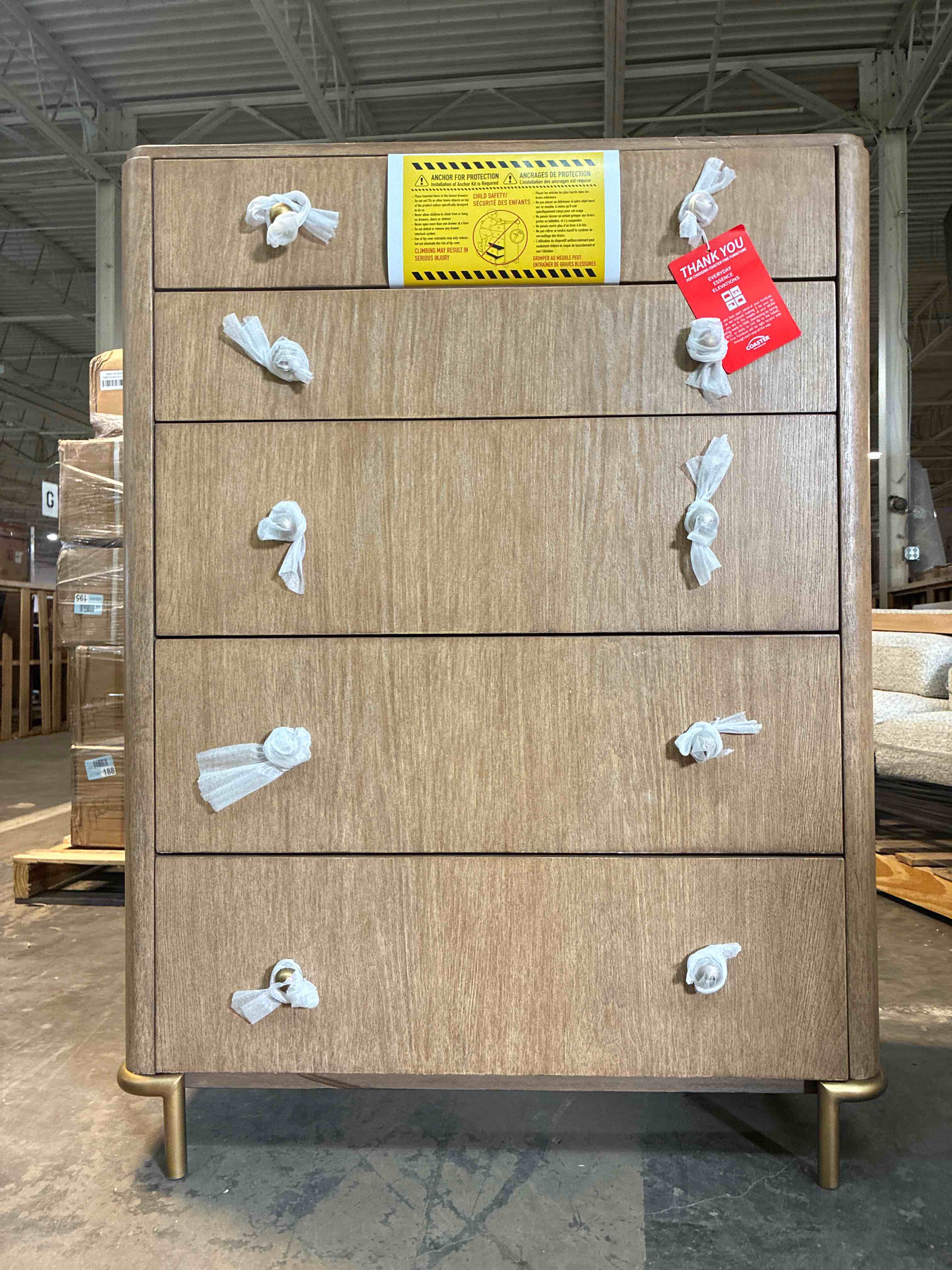 Condition photo showing New/Like New for coaster home furnishings - arini light wood grain 5-drawer chest with aged brass metal hardware, gold legs and felt-lined top drawer, sand wash. 50.25'' h x 38'' w x 18'' d