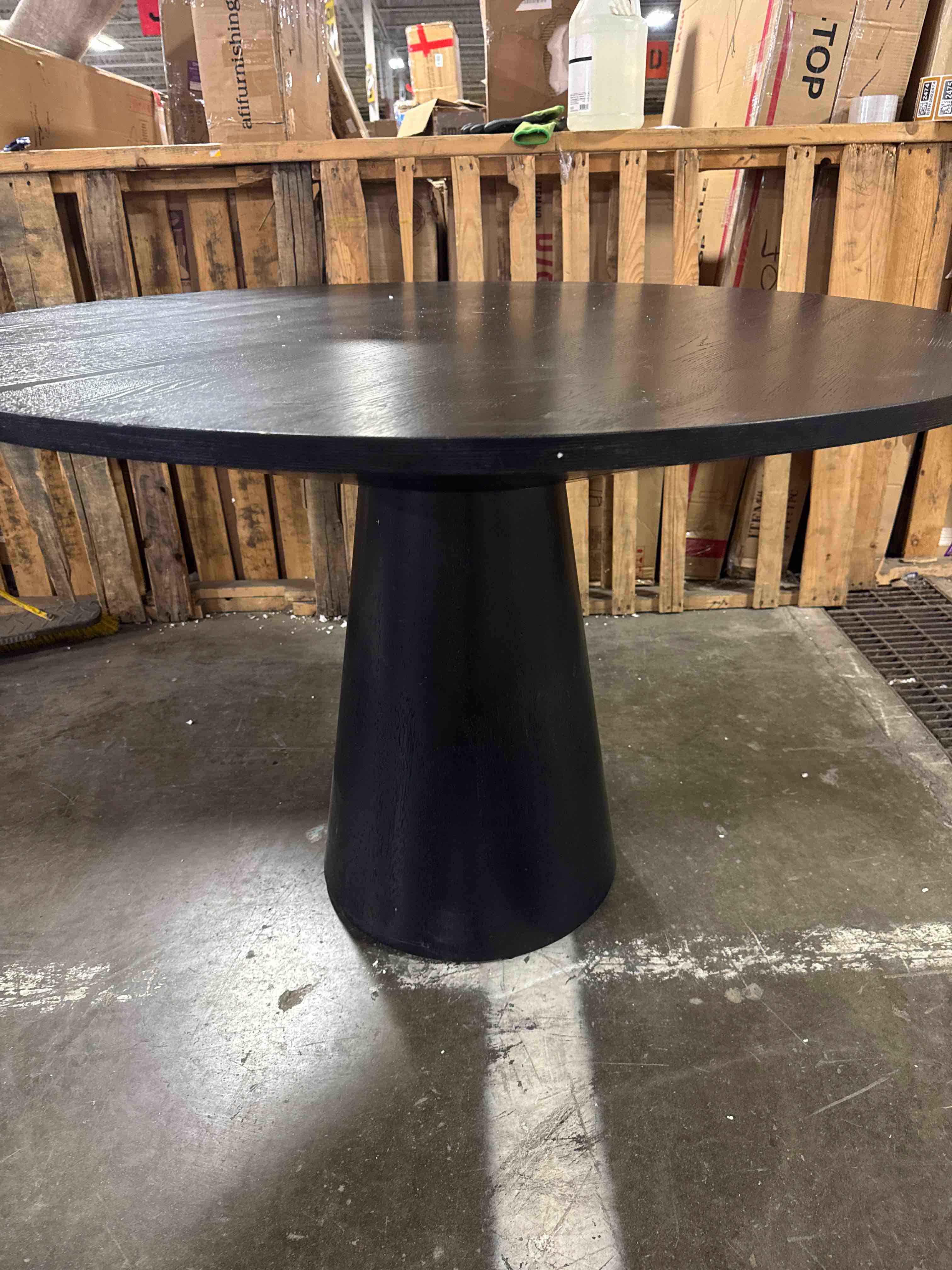 Condition photo showing As Is for Aron Round Black Solid Wood Dining Table, Overall Dimensions 30'' H X 51'' W X 51'' D Crack On Top Edge Of Base Piece, Minor Chips And Scrapes Around Edges Of Tabletop, Base Needs Reinforced