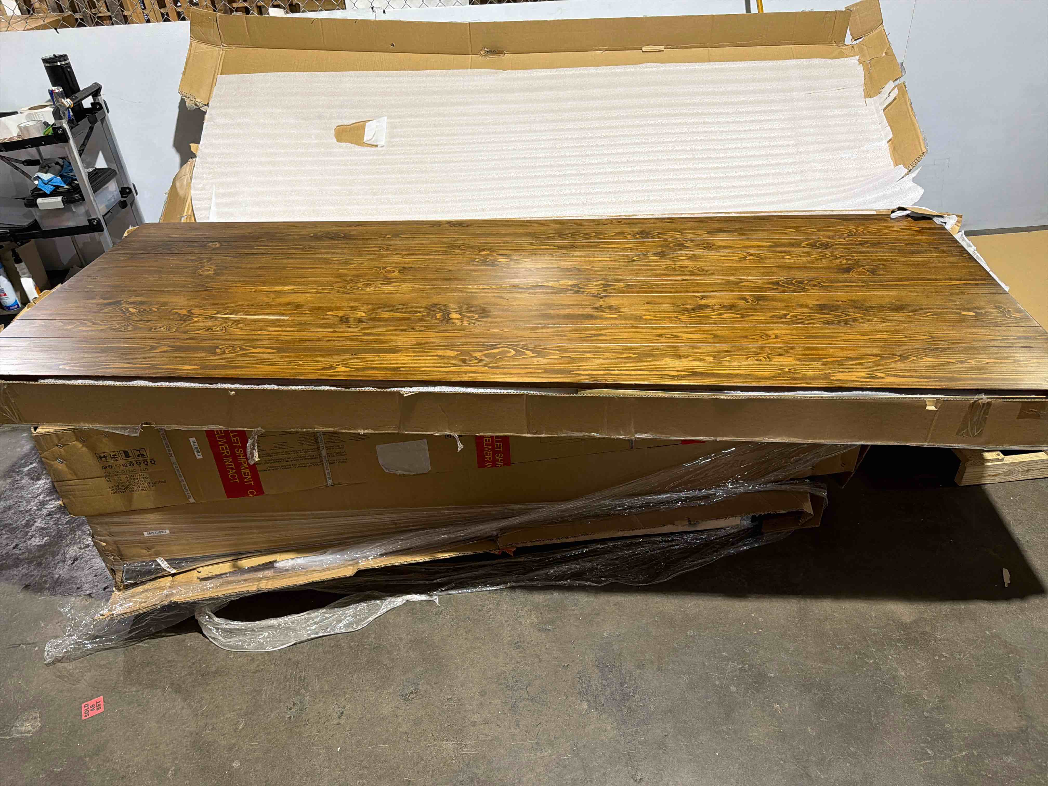 Condition photo showing As Is for hercules series 8 ft. x 40 in. solid pine folding farm table in a antique rustic stain finish, folded size 96"w x 5"d x 29.75"h, base size 28.25"w x 65.25"l, tabletop has a large prominent crack down the middle plank of the table, table has a few other cracks on edges of table, 9 to 10 inch scuff on tabletop(pictured), is still usable in current condition, 