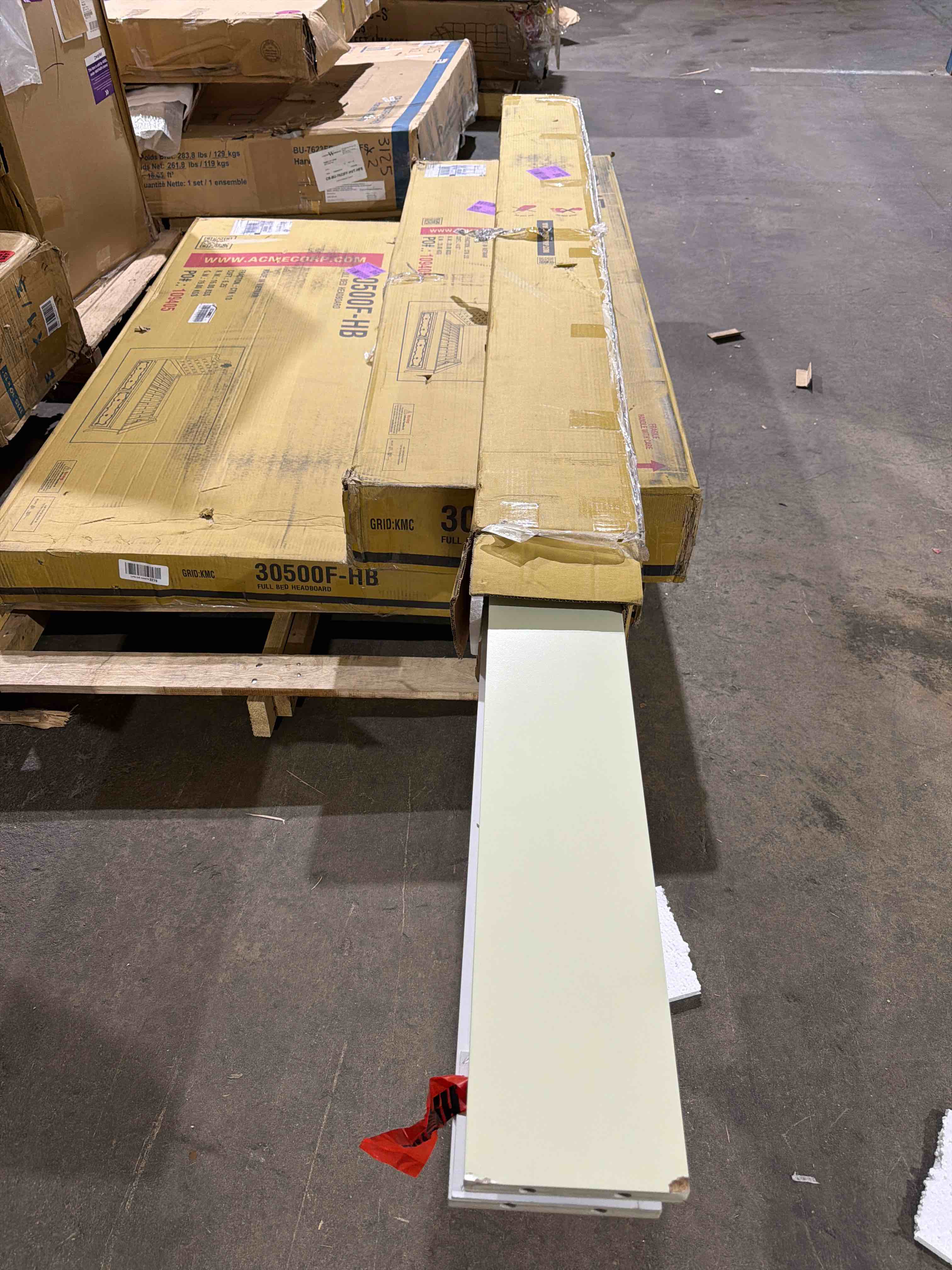 Condition photo showing As Is for edalene upholstered full bed in pearl white, upholstered headboard with button tufted accents, floral decorative carvings, side rails have some chipping on the corners(pictured),  footboards leg is broken on one side (piece is in box) and cracked on the other(pictured), trundle sold separately, 3 boxes total