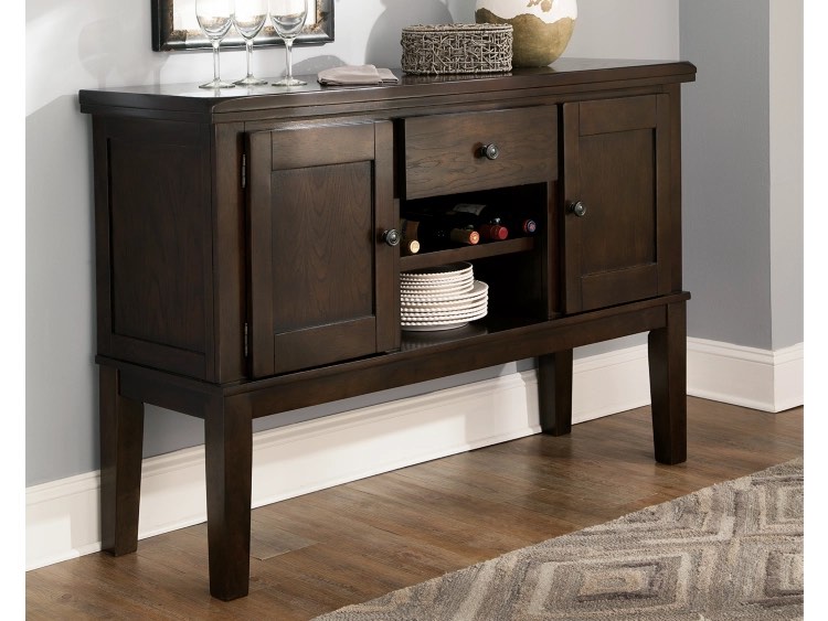Signature Design by Ashley Haddigan Dark Brown Solid Wood Traditional Dining Room Buffet Cabinet with 2 Cabinet Doors, Adjustable Shelving Optional, Middle Wine Rack and Drawer with Bronze Brushed Metal Knobs. Some small scratches inside right side cabinet, Wine rack need rehinged. 56” W x 18” D x 38.25” H